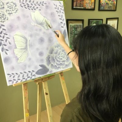 A teen painting a textured flower artwork